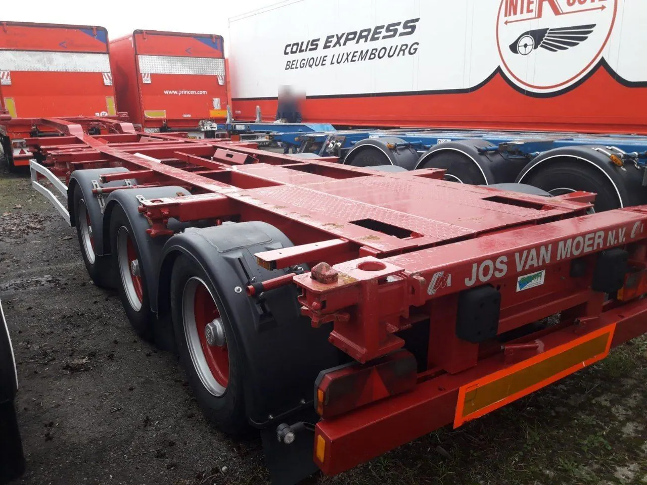 Red tri-axle container chassis in a yard